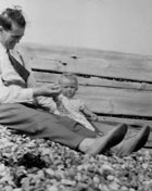 An old photo of a man on a beach with his baby
